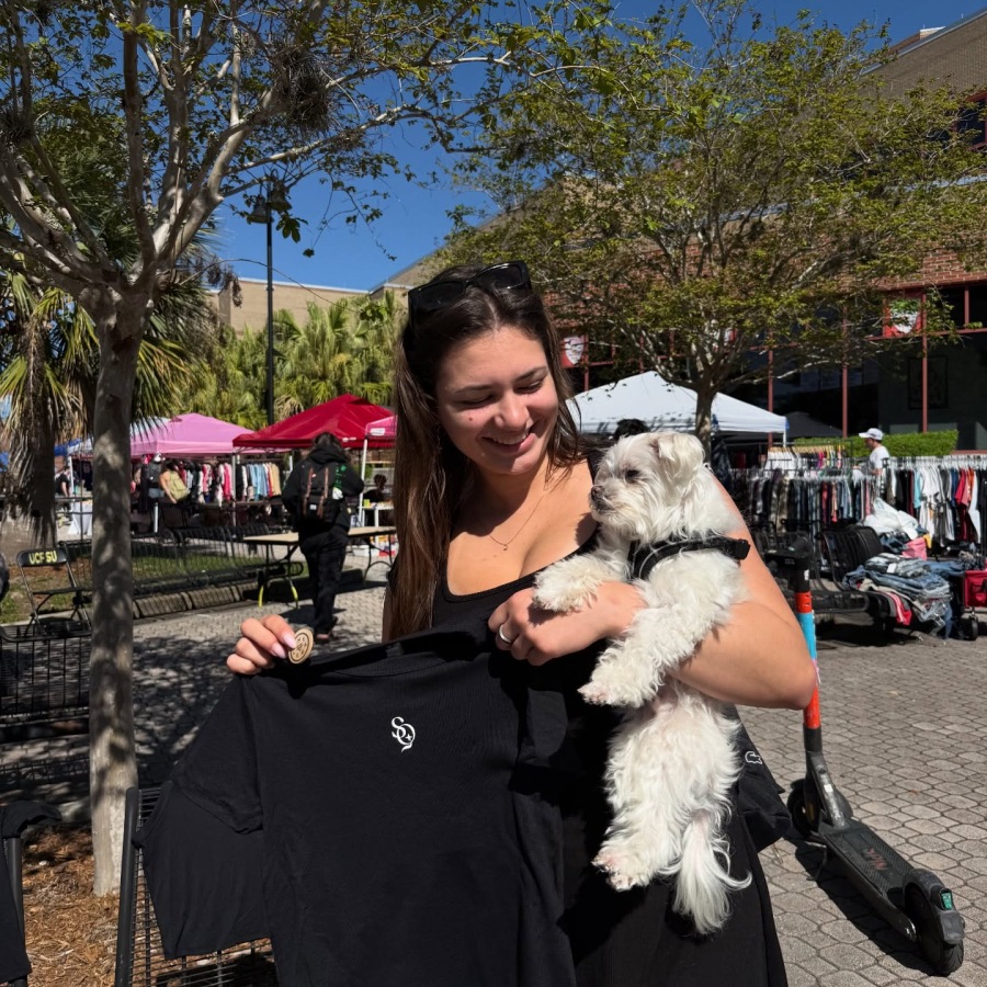 a person holding a dog and a T-shirt outside