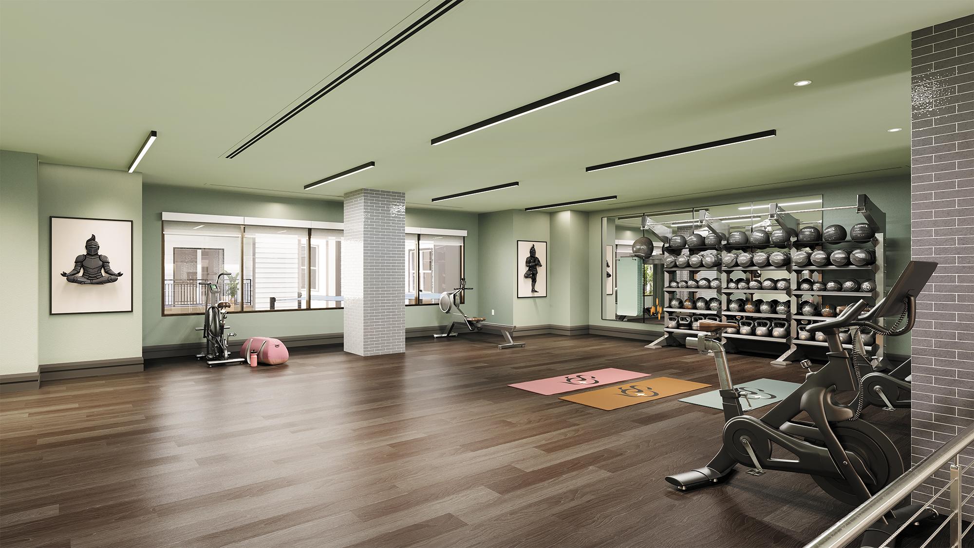 Sterling Quadrangle A spacious fitness studio with yoga mats, exercise bikes, a weight rack, and wall art.